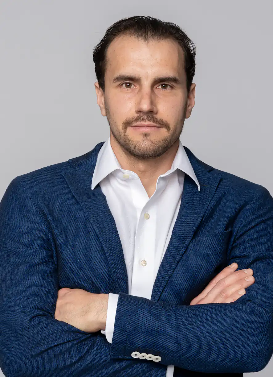 Ritratto del Dr. Guido Gabriele in giacca blu e camicia bianca, a braccia conserte, su fondo chiaro