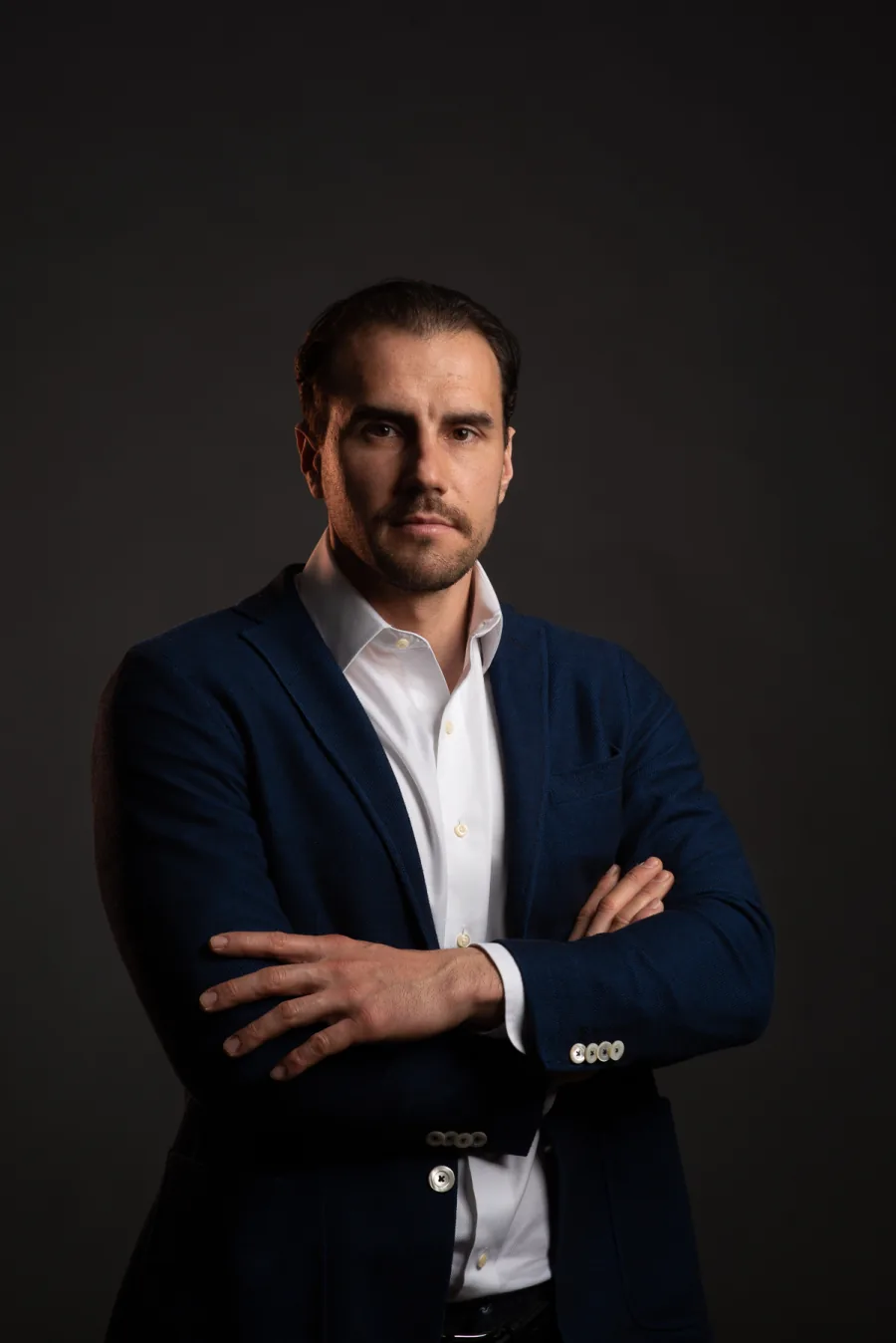 Ritratto del Dr. Guido Gabriele in giacca blu e camicia bianca, a braccia conserte, su fondo scuro
